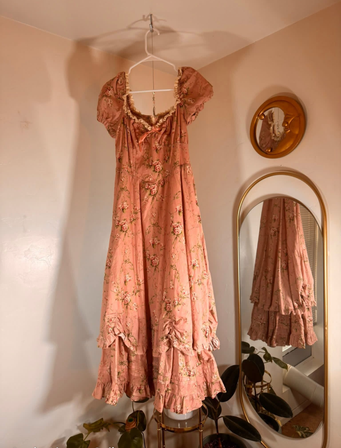 Peach-colored floral dress hanging on a rack with a mirror reflection.